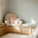 Chambre d’enfant apaisante avec mobilier en bois clair, coin lecture confortable, rangements bas et une lumière douce et naturelle.