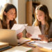 Une mère et une lycéenne comparent des fiches vierges et un ordinateur sur une table lumineuse, dans un espace d’étude calme et organisé.
